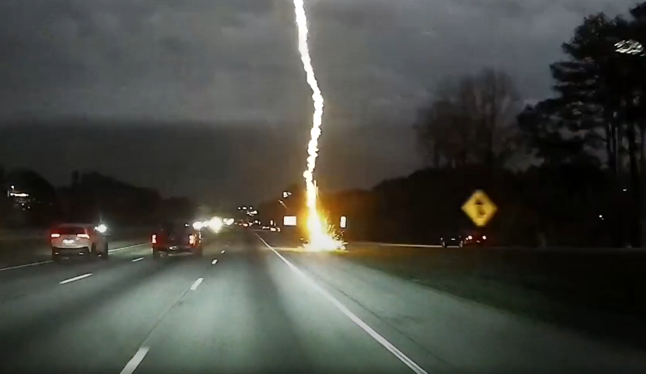 Lightning striking near a highway during night time.
