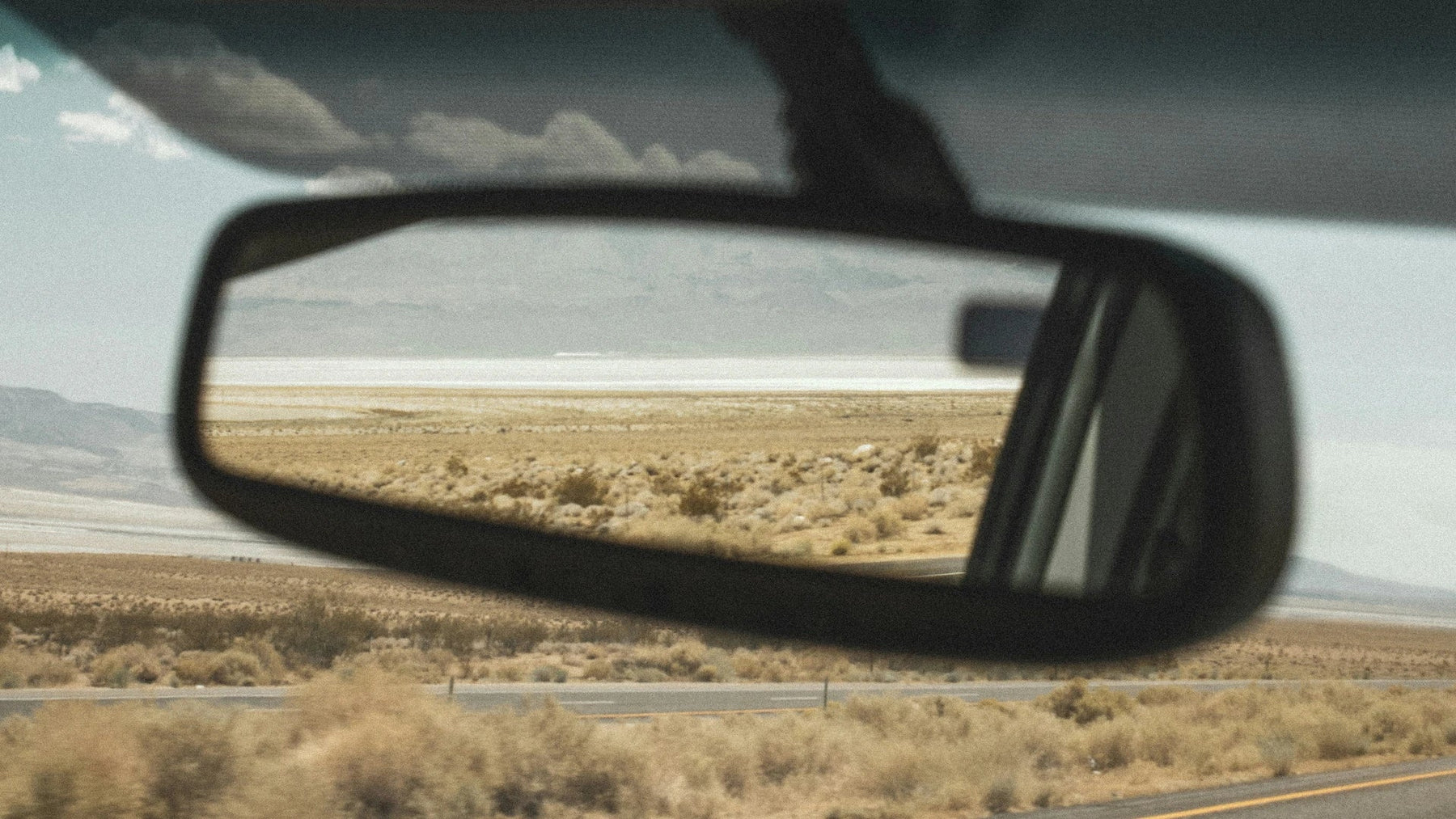 Road and desert landscape reflected in a car’s side mirror