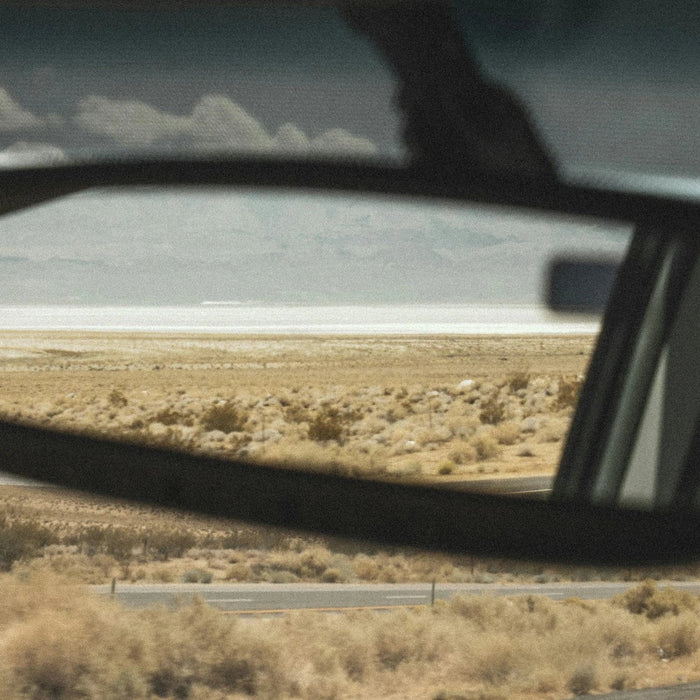 Road and desert landscape reflected in a car’s side mirror