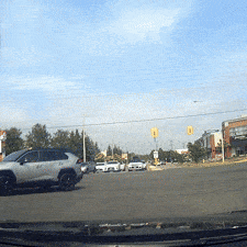 A car navigating a busy intersection under a clear sky.