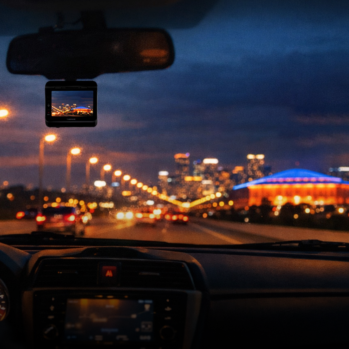 View from a car driving at night, city lights ahead.