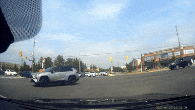A car navigating a busy intersection under a clear sky.