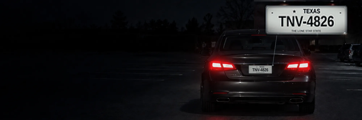 A car at night in a dark parking lot with a magnified licence plate