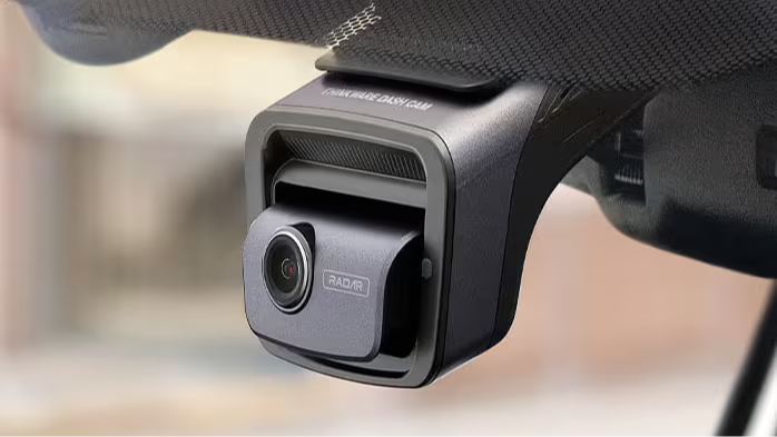 A Thinkware dash cam installed behind a rear-view mirror